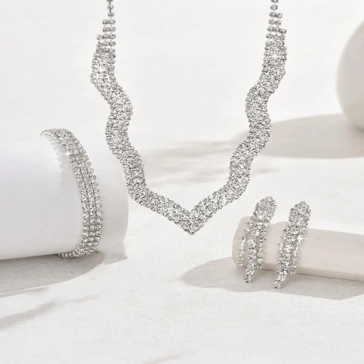 Silver necklace and earrings set on a white surface
