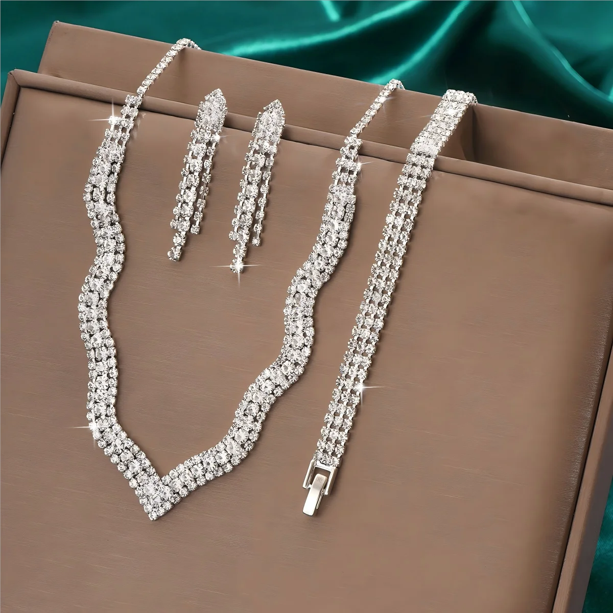 Silver jewelry set with necklace, bracelet, and earrings on a brown surface.