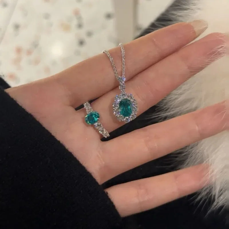 Two emerald green gemstone necklaces on a hand against a neutral background