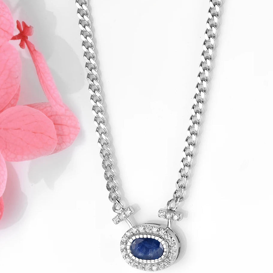 Silver necklace with a blue gemstone pendant on a white background with pink flowers.