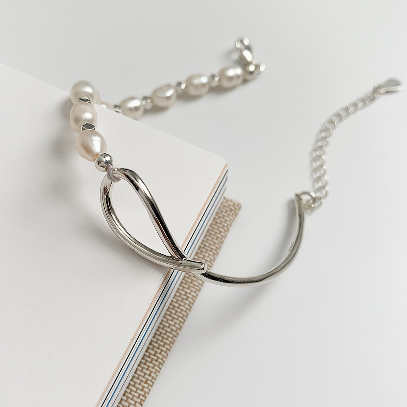 Silver necklace with a unique pendant on a light gray background
